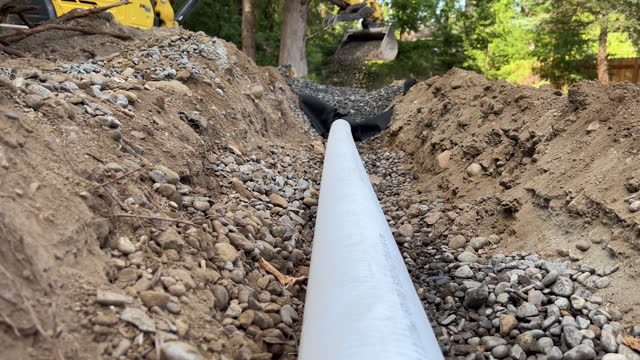 Excavator Installing Residential Drainage Gravel PVC Pipe in Ditch