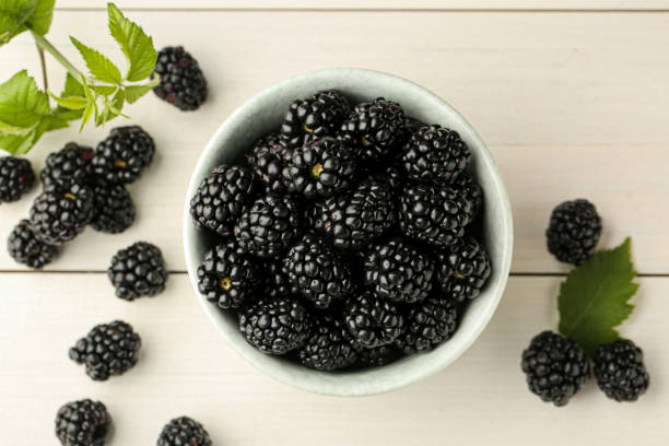 istock Fresh ripe blackberries on white wooden table, flat lay 1484939823