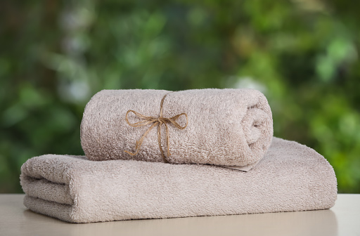 Beige soft towels on white table outdoors, closeup