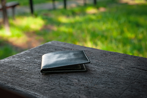 Black wallet on bench outdoors. Lost and found