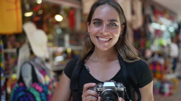 Portrait of traveler mid adult woman at an outdoors market with camera