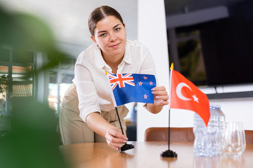female assistant in  audience for international negotiations arranging  flags of  participating countries â Turkey and Australia