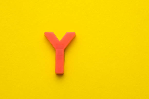 Alphabet letter Y - Peach colored plastic piece on yellow foamy background