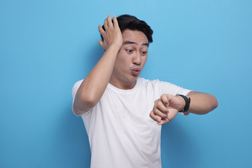Portrait of funny Asian man shocked worried to see his wrist watch, late time concept
