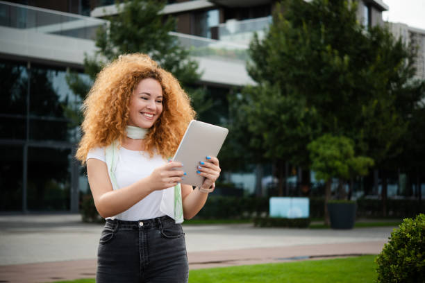 istock Beautiful redhead woman walking and making a video call on a tablet 1484959160