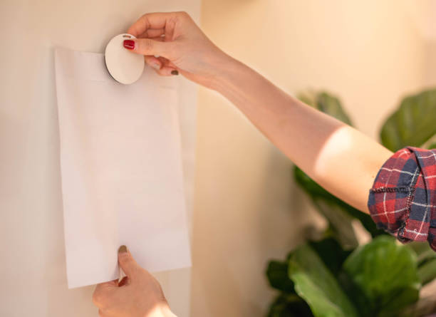 Female hand attaching pieces of white paper to the magnetic board to remind the important notice. stock photo