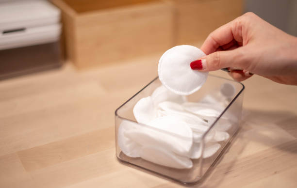 Female hand with new clean cotton pad from the plastic box preparing to clean face. stock photo