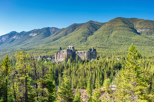 Banff Springs Hotel in the forest in the Canadian Rockies, Banff, Alberta, Canada on a sunny day.