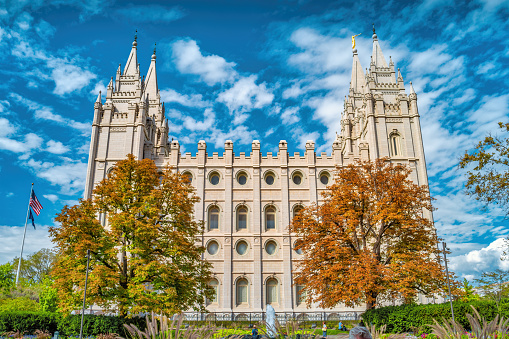 People stand in front of Salt Lake Temple in Salt Lake City, Utah, USA on a sunny day.