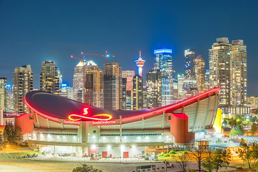 Skyline of Calgary Alberta Canada with the illuminated Scotiabank Saddledome arena at night.