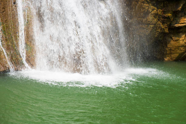 istock Beautiful waterfall in forestry with blue water with ripples on the surface. Blurred transparent blue colored clear calm water surface texture with splashes and bubbles. Water waves with shining. 1484976575