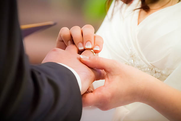 istock Groom puts ring on brides finger in church 148497829