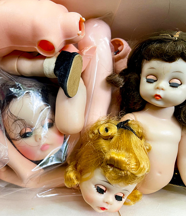Dolls broken into pieces looking sad. Full frame color image.