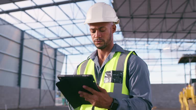 Serious man, construction worker and planning on tablet at site, project management and building logistics. Thinking, male and engineering on digital technology for industrial architecture renovation