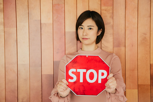 A woman holding a stop board at a traffic sign. She wants it to stop.