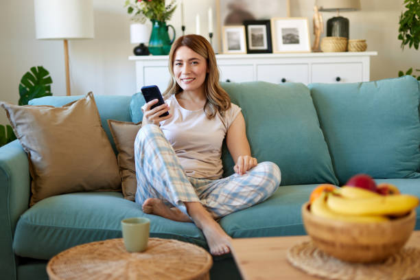 istock Happy woman text messaging on mobile phone while relaxing at home 1485004009