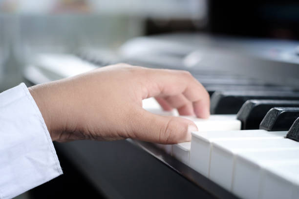 子供の左手がピアノの鍵盤のコードを押す接写。楽器の練習。 - piano keyboard instrument one person piano key ストックフォトと画像