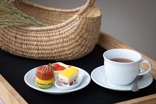 A tray of afternoon tea, English traditional drink with dessert, macarons and cake on white plate.