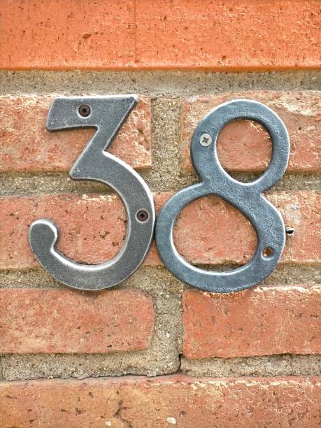 istock thirty-eight, 38 in silver colored metal number, number set on a red brick wall with cement seam, copy space. 1485010614