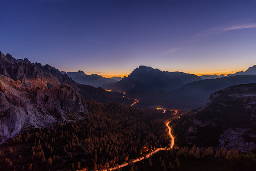 Twilight in the mountains in south tyrol with light trail on mountain valley road