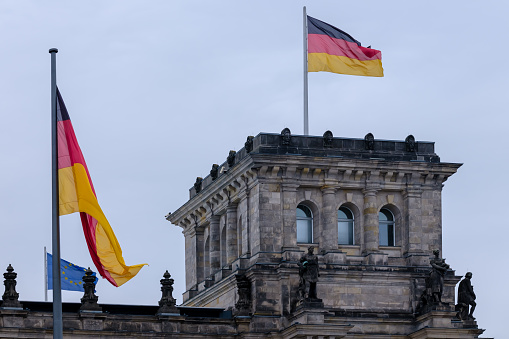 Berlin, Germany - April 18, 2023 : View of the top of the Reichstag, the German parliament in Berlin Germany, the EU flag and the German flag