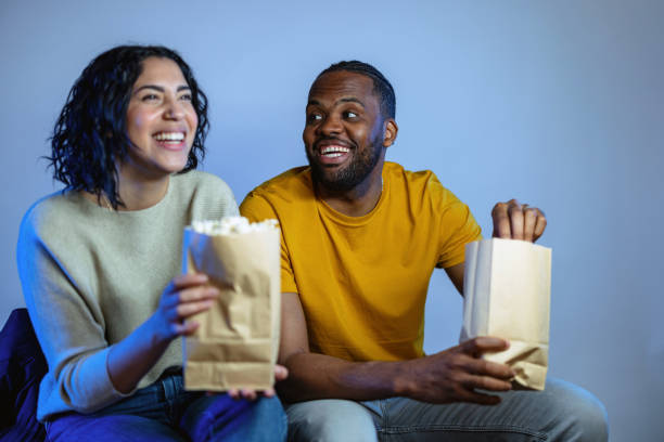 istock Young Diverse Couple Eating Popcorn and Laughing While Watching A Movie 1485019093
