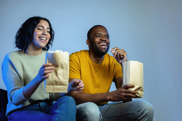 istock Young Diverse Couple Eating Popcorn and Laughing While Watching A Movie 1485019128