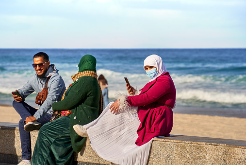Sousse, Tunisia, January 19, 2023: Family in demure traditional dress covering head and face on the seafront promenade