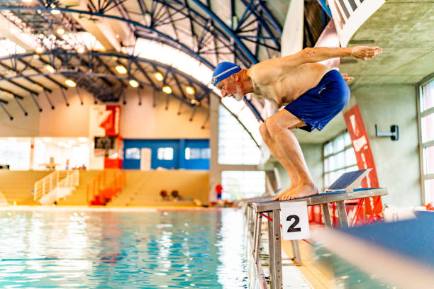 istock Senior man preparing for a jump in an indoor pool 1485021419