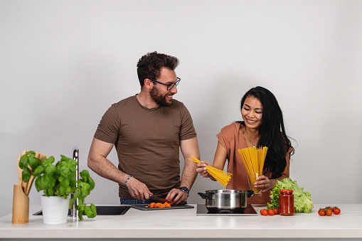 Cheerful And Happy Diverse Couple Cooking In The Kitchen Together