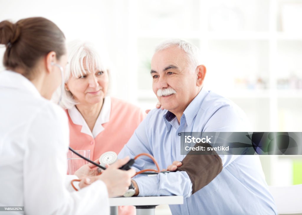Senior couple at doctor's office. Senior man with his wife at doctor's office measuring blood pressure. Blood Pressure Gauge Stock Photo