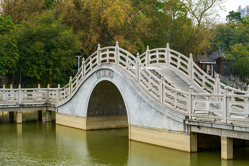 Chinese style pedestrian stone arch bridge over lake in park