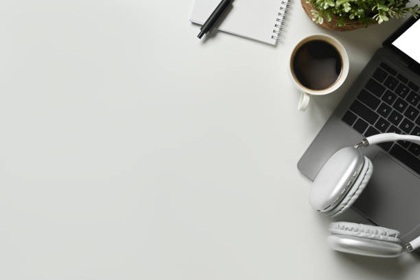 istock Top view of laptop, headphone, empty notepad and coffee cup on white table. Copy space for your text. 1485028883