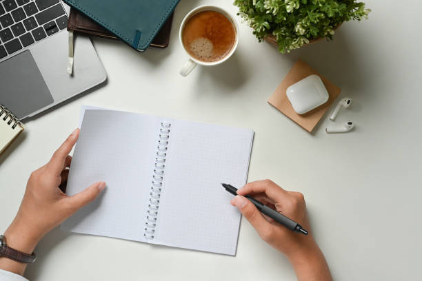 istock From above view of female worker writing on empty spiral notepad at her working desk. 1485028911