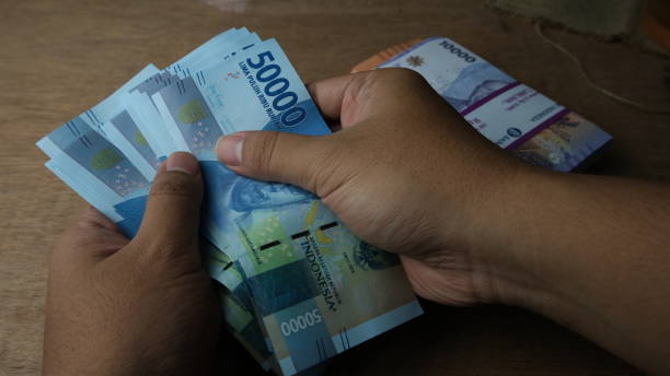 istock Close up of hand counting Indonesian Rupiah bank notes 1485029126