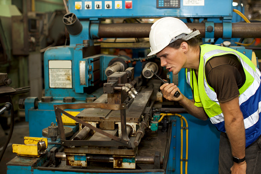 Mechanical engineer or worker in safety set working with heavy machine in a factory to repair the system