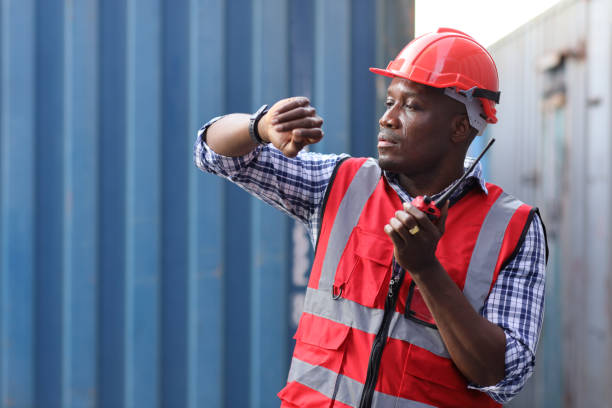 istock Foreman look and speak to wristwatch control loading containers box. Professional engineer or worker with safety hat work at container cargo site and checking industrial container cargo freight ship. 1485032877