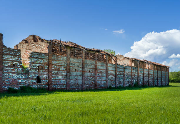 A unique perspective shot from inside a derelict barn, showing the dramatic collapse of the roof with a bright blue sky visible through the gaps.