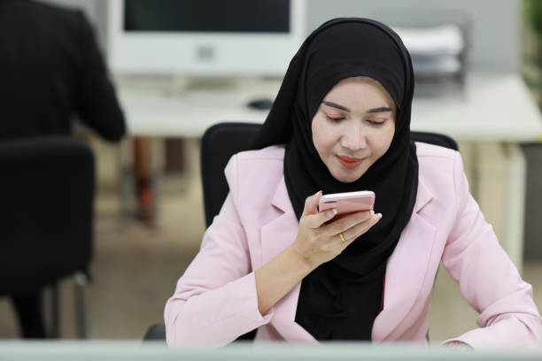 istock Attractive professional asian muslim female employee worker sitting, using laptop computer with coworker at workplace. Businesswoman talking on smart mobile phone and communicate with client. 1485034986