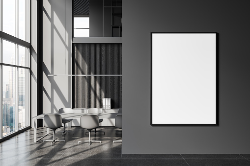 Dark office interior with meeting board, chairs and shelf with documents. Panoramic window on skyscrapers. Mock up canvas poster on partition. 3D rendering