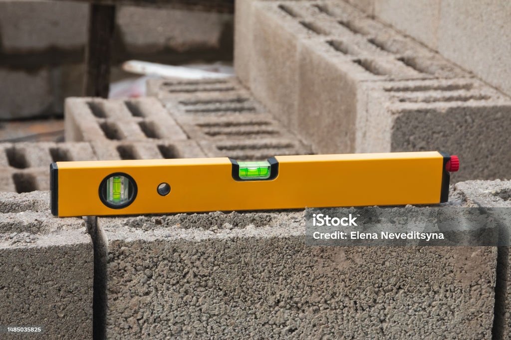 The bubble construction level lies on a cinder block construction stone. It is used to assess the compliance of surfaces with a vertical or horizontal plane, as well as to measure the angular deviatio Level - Measurement Tool Stock Photo