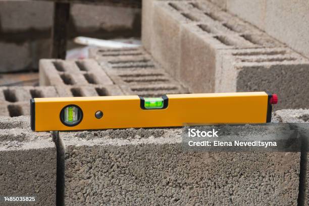 The Bubble Construction Level Lies On A Cinder Block Construction Stone It Is Used To Assess The Compliance Of Surfaces With A Vertical Or Horizontal Plane As Well As To Measure The Angular Deviatio Stock Photo - Download Image Now