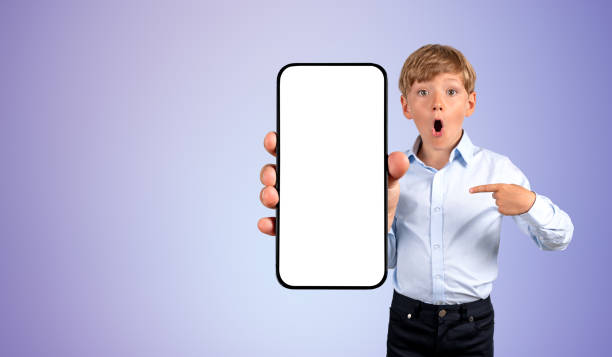 istock Emotional boy finger pointing at large phone blank mockup displa 1485036993
