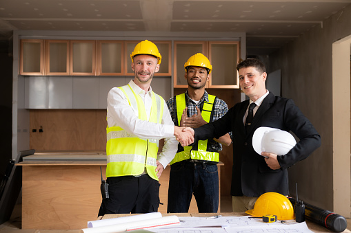 Architect and construction worker engineers shaking hands while working for teamwork and cooperation concept after completing agreement on office construction site.