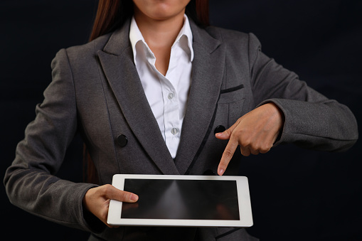 Attractive professional female hands standing and showing blank screen on tablet  for advertising on black background isolated