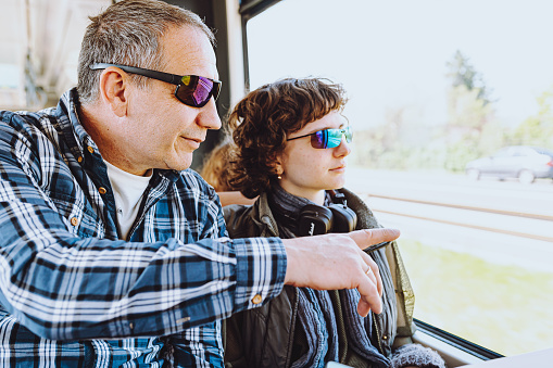 hipster teen girl and her father in sunglasses travel by train. They look out window together. Dad imitates his daughter by dressing in modern and fashionable way. Spending time with dad, father's day, single father with teenage daughter
