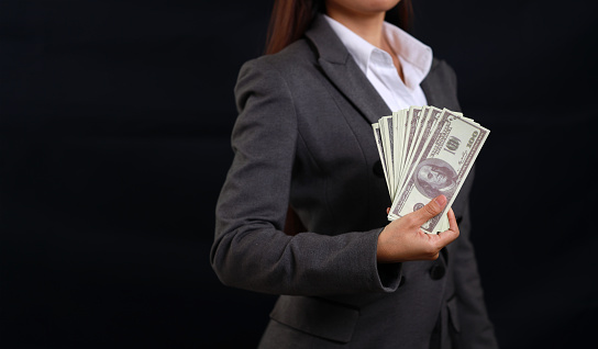 Attractive professional female hands standing and showing bank note for advertising on black background isolated