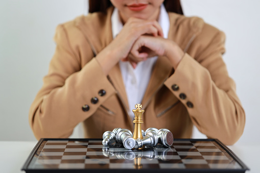 Businesswoman hands in classic suite sitting and clasping hands planning strategy with chess on white table. Decision and achievement goal concept.