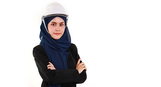 Happy and smart muslim asian engineer standing and arms cross with confident in studio. Isolated white background image with beautiful face female and hard hat in hijab. Advertisement portrait concept
