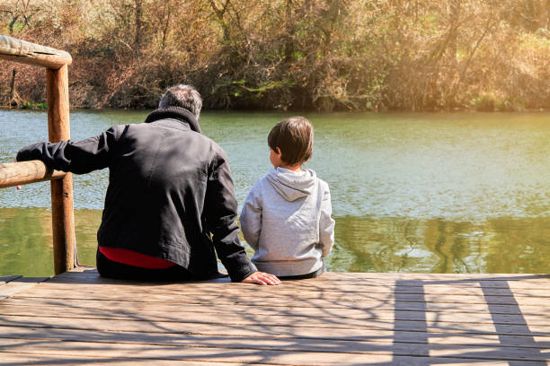 istock Unrecognizable father and son stays sitting on a dock over a river 1485041147